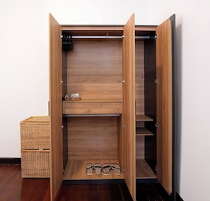 Une armoire en bois, dont les portes sont ouvertes, laissant apparaître des étagères et un porte-chaussures.
