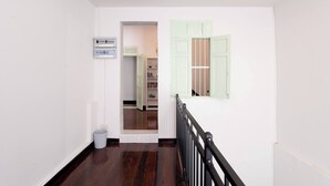 A hallway with a staircase, a trash bin, and a power outlet. - Spacious Heritage House Prime Location Family Stay (Bangkok)