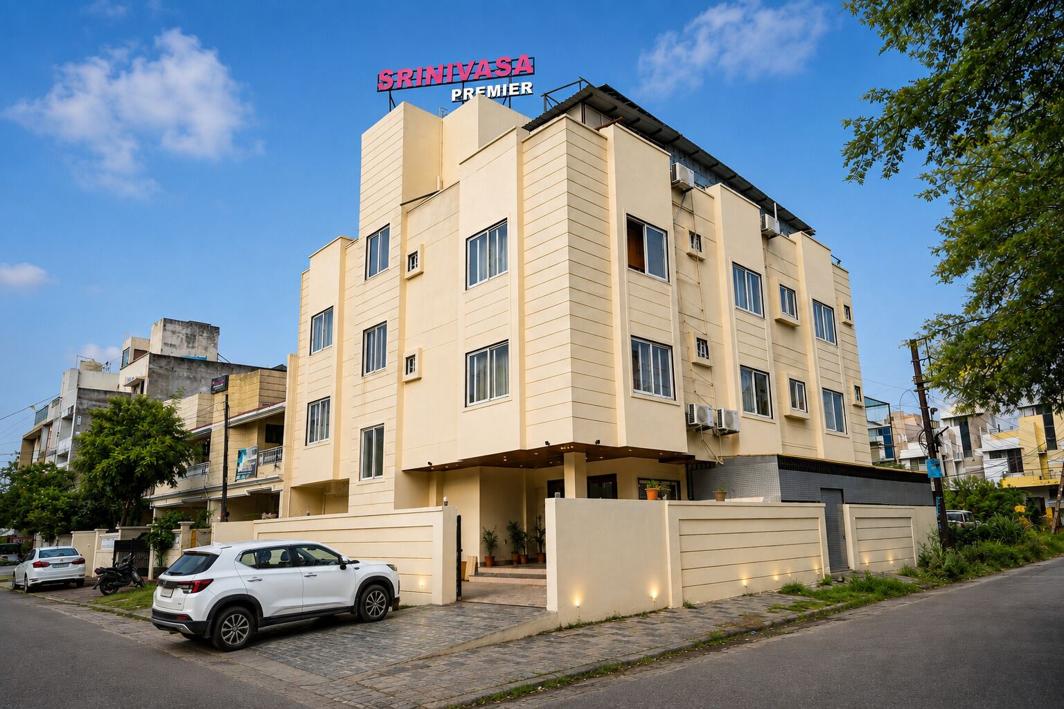 Un hotel de varios pisos con un letrero llamativo que dice 'Srinivasa Premier'.
