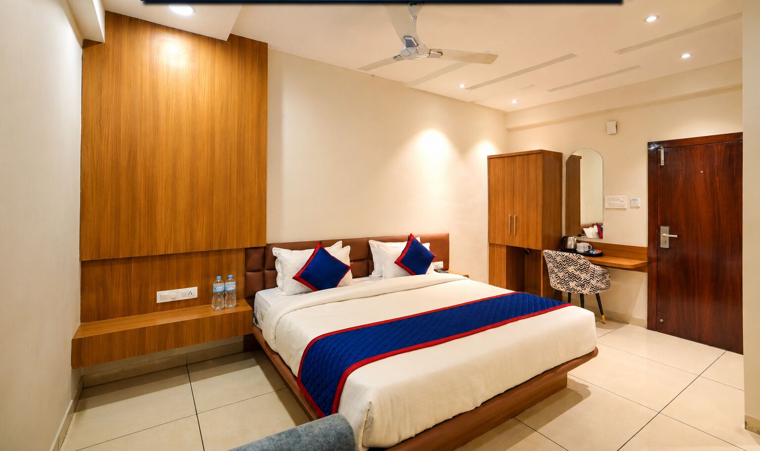 Ein Hotelzimmer mit einem großen Bett, einem Holzschrank, einem Nachttisch und einem kleinen Schreibtisch mit Stuhl.