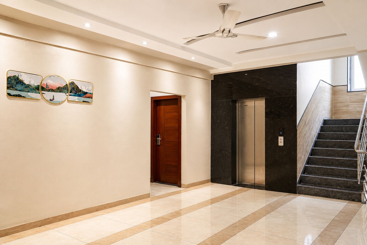 A hotel lobby with a marble floor, a wooden door, an elevator, and a staircase with metal railings.