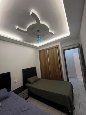 Une chambre à coucher comprenant un lit, une table de chevet, une armoire et un luminaire au plafond.