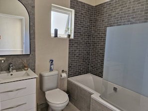 A bathroom with a toilet, sink, and bathtub.
