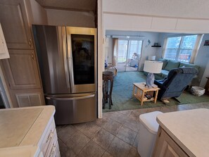 A kitchen with a stainless steel refrigerator, a dining area with a table and chairs, and a living room with a sofa and a lamp. - Cozy ICWW waterfront 2-bedroom cottage in soothing Myrtle Beach (Myrtle Beach)