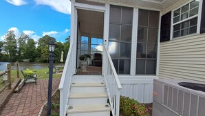 A house with a covered porch, a staircase leading to the entrance, and a view of a lake. - Cozy ICWW waterfront 2-bedroom cottage in soothing Myrtle Beach (Myrtle Beach)