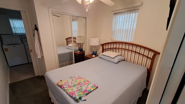 A bedroom with a single bed, a ceiling fan, a bedside table with a lamp, and a window with blinds. - Cozy ICWW waterfront 2-bedroom cottage in soothing Myrtle Beach (Myrtle Beach)