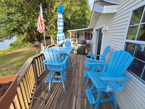 A deck with blue Adirondack chairs, a grill, and an American flag. - Cozy ICWW waterfront 2-bedroom cottage in soothing Myrtle Beach (Myrtle Beach)