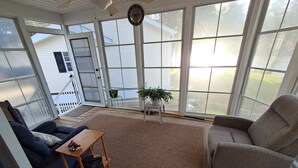 A sunroom with a large window, a ceiling fan, a clock, and a potted plant. - Cozy ICWW waterfront 2-bedroom cottage in soothing Myrtle Beach (Myrtle Beach)