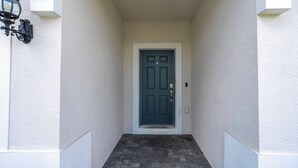 A narrow entrance with a dark door, white walls, and a small step leading up to the door. - Stunning Windsor Island 10BR (Davenport)