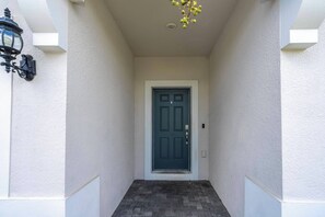 A narrow entrance with a dark door, white walls, and a small step leading up to the door. - Stunning Windsor Island 10BR (Davenport)
