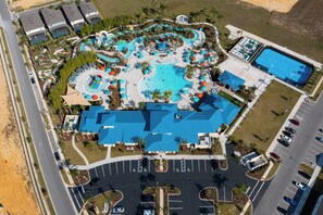 Vista aérea de un complejo turístico con una gran piscina, varias toboganes acuáticos y una cancha de baloncesto.