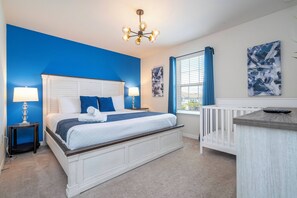 A bedroom with a large bed, bedside lamps, a crib, and artwork on the walls. - Stunning Windsor Island 10BR (Davenport)