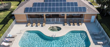 Ein Gebäude mit Schwimmbecken, Solaranlage und einer überdachten Liegefläche.