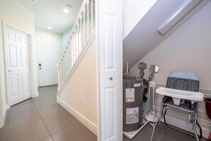 A hallway with a staircase, a water heater, and a baby changing station. - Charming 3 BR with pool at Serenity (Clermont)