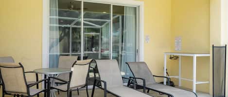 An outdoor seating area with chairs and tables, a glass door, and a pool safety sign.