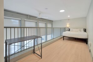 A bedroom with a bed, a nightstand, a lamp, and a window with blinds. - Chic City Loft - Nearby Parking - Hospitals - 2F (Louisville)