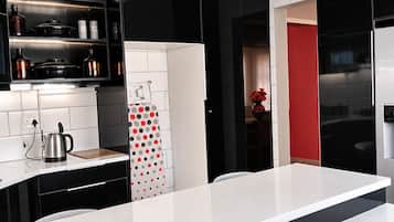 A modern kitchen with black cabinets, a white countertop, and a red accent wall.
