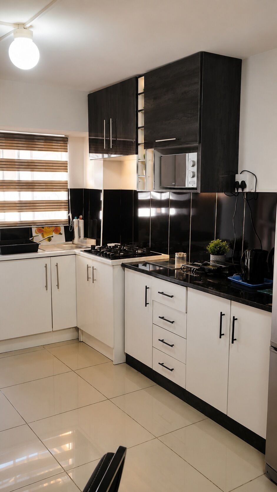 A modern kitchen with white cabinets, a black countertop, and a built-in microwave.