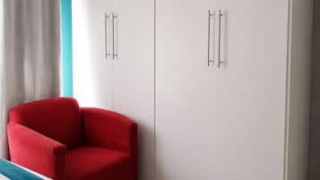 A bedroom with a bed, a red chair, and a wardrobe.