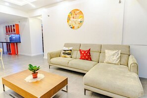 A modern living area with a sofa, a coffee table, and a wall-mounted artwork. - Relaxing Condo Stay in Seibu Tower (Taguig City)