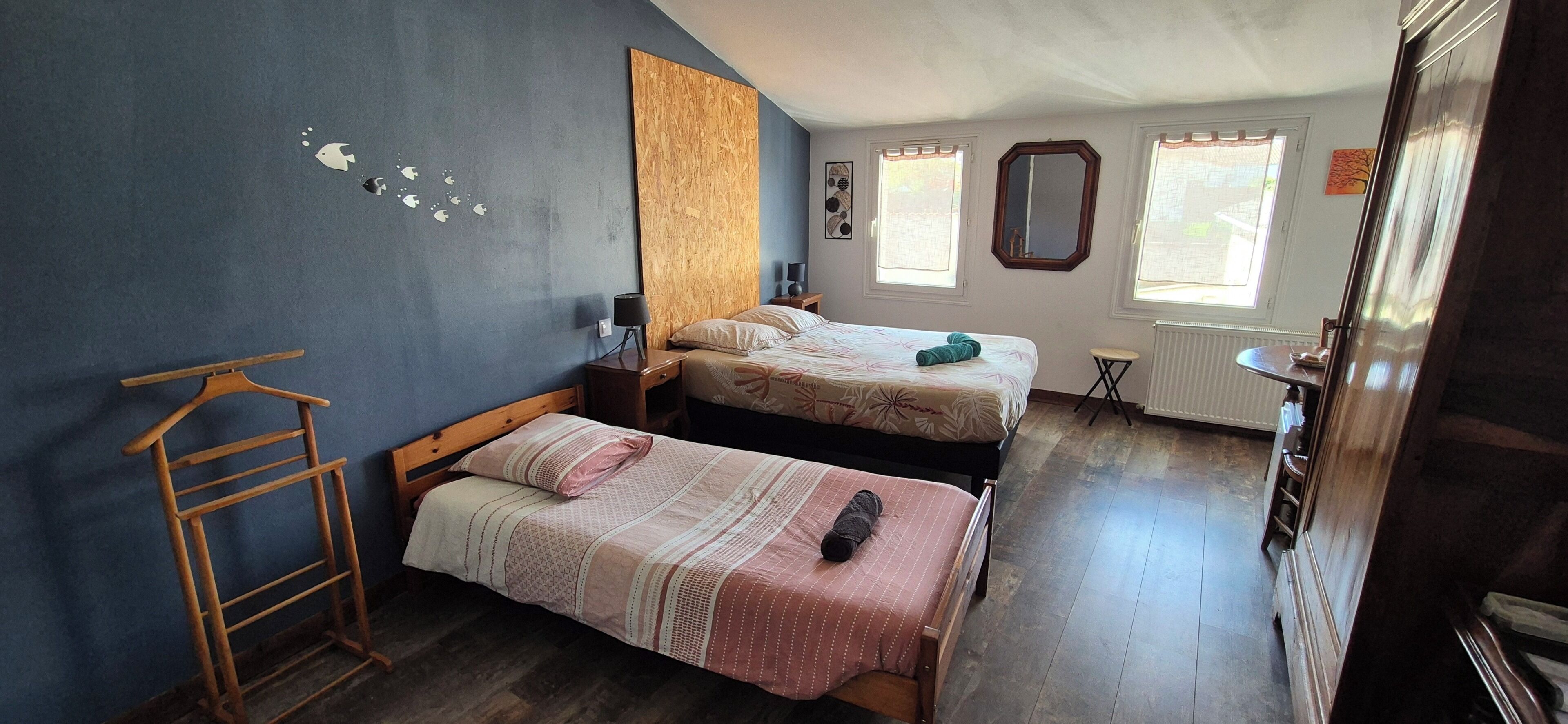 A room with two beds, a wooden ladder, a radiator, and a window with a view.