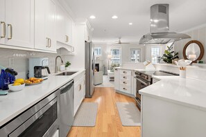 A modern kitchen with stainless steel appliances, white cabinetry, and a central island. - *New* The Landing: OC | Boardwalk | Sleeps 10! (Ocean City)
