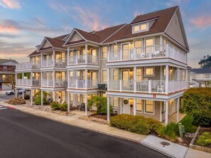 A row of two-story buildings with balconies, a street in front, and a clear sky. - *New* The Landing: OC | Boardwalk | Sleeps 10! (Ocean City)