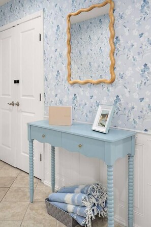 Una habitació amb un taulell blau clar, un quadre amb marc i un mirall decoratiu a la paret.