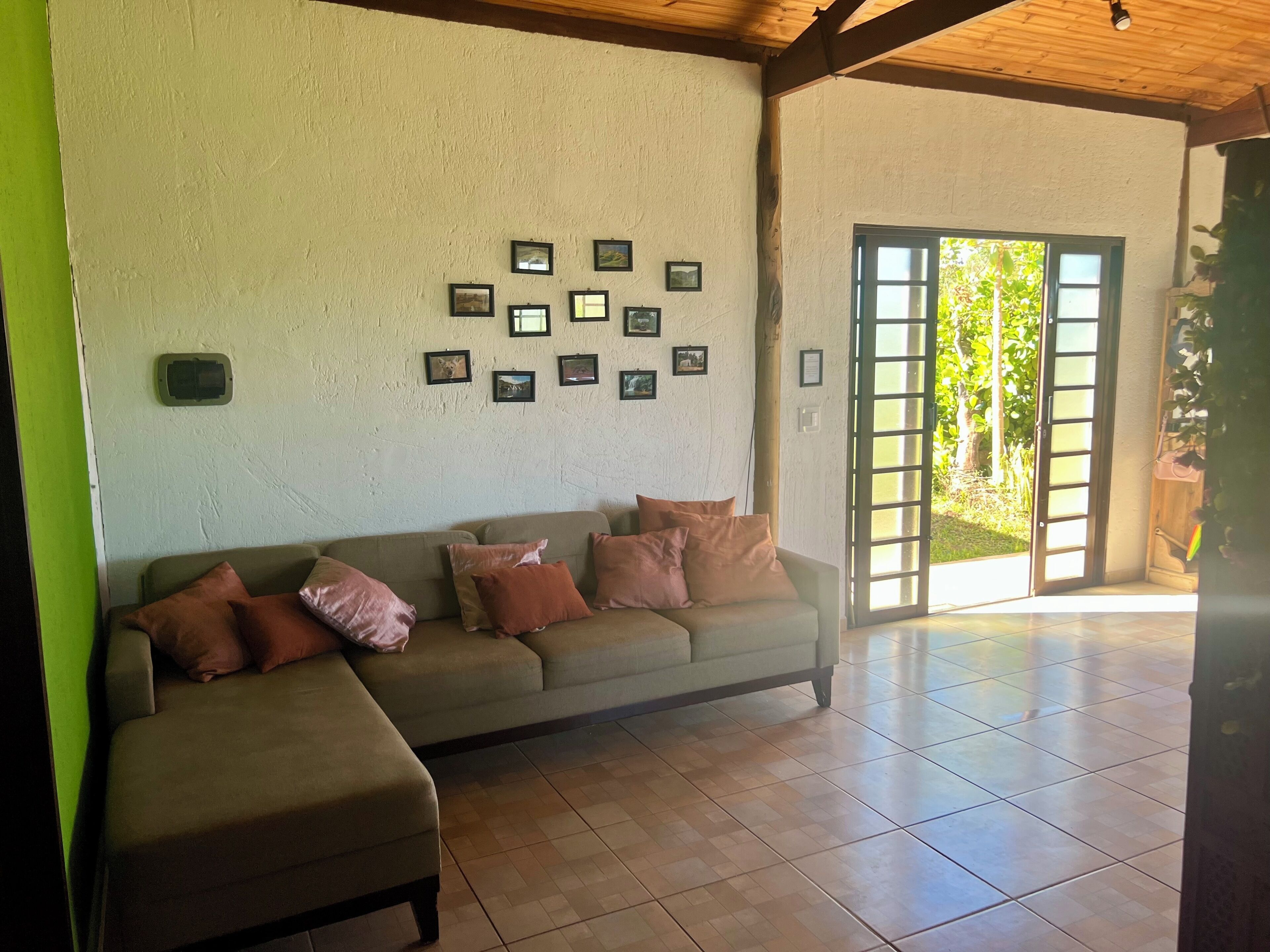 A room with a sofa, a wall-mounted air conditioning unit, and a sliding glass door leading to an outdoor area.