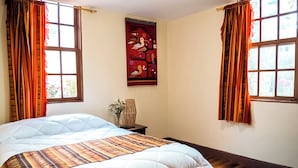 Un dormitorio con una cama grande, un tapiz en la pared y cortinas.