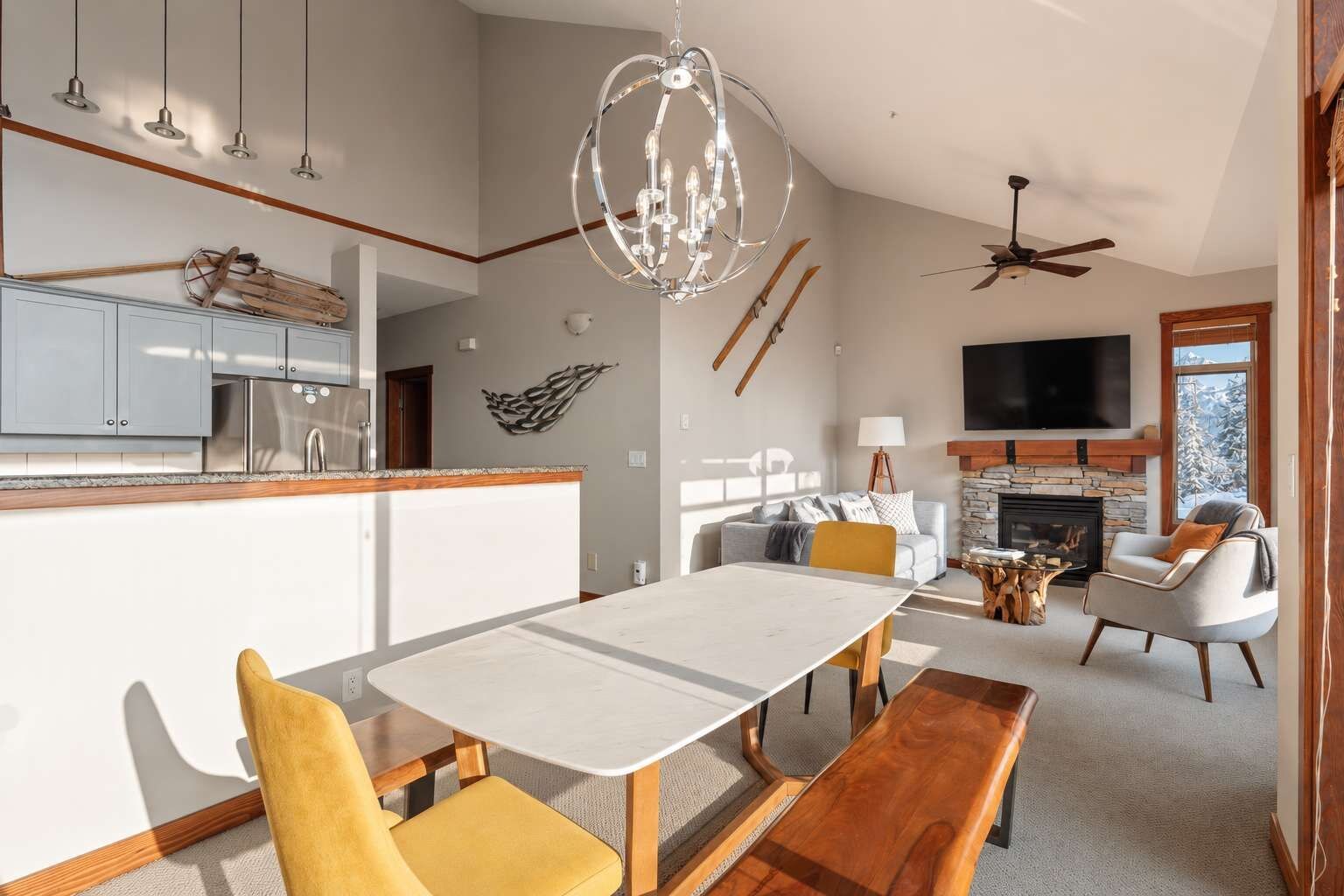 A modern living room with a fireplace, a dining area, and a kitchen with a built-in refrigerator.