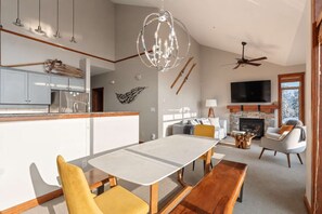 Un soggiorno moderno con camino, zona pranzo e cucina con frigorifero integrato.
