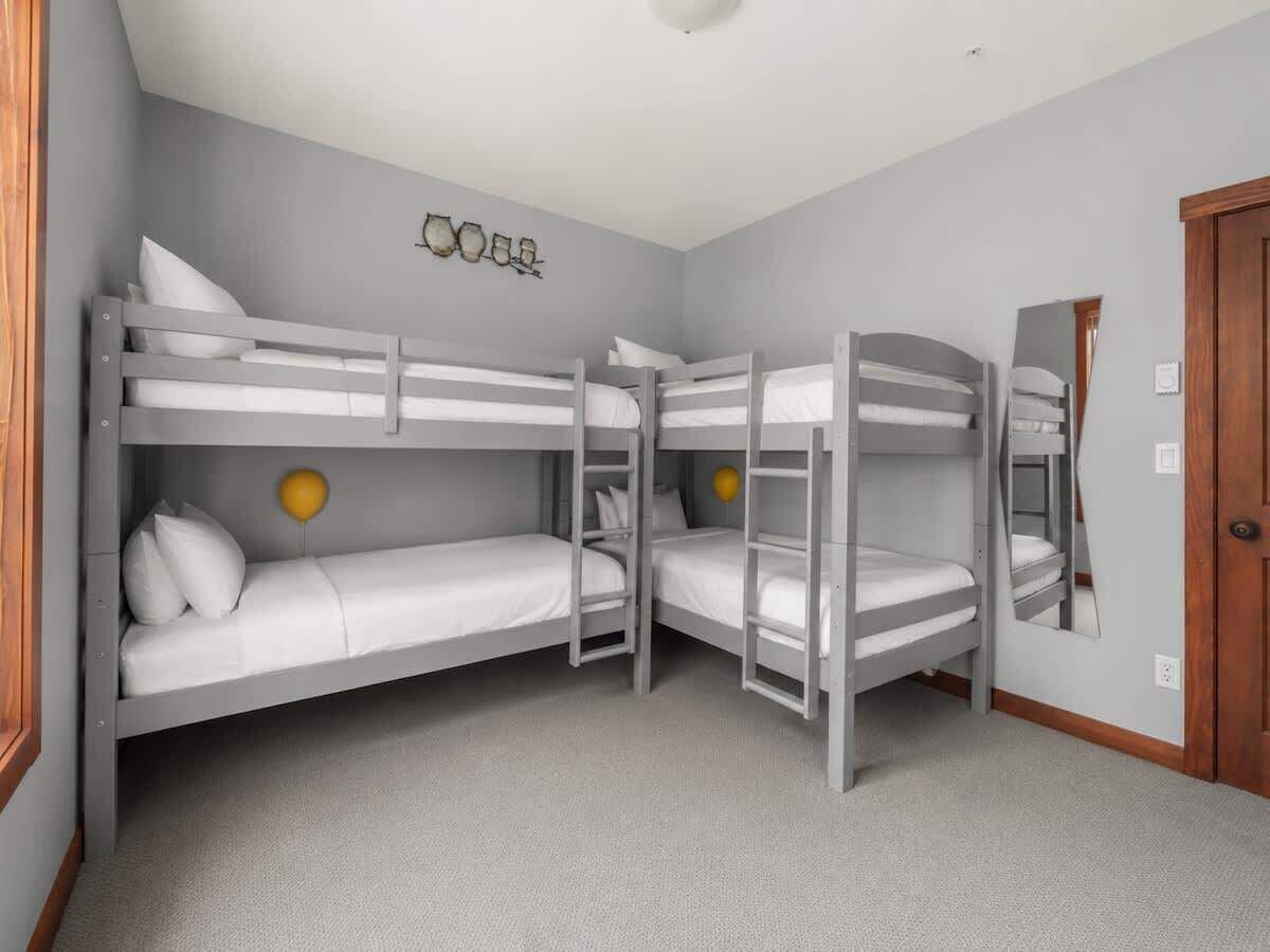 A room with bunk beds, a wooden door, and a wall-mounted mirror.