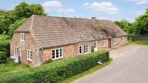 A two-story brick house with a tiled roof, a front driveway, and a well-maintained hedge. - Historical Bullfinch Cottage - Amazing Day Trips! Minutes from Beach! (Tim Kirkeby)