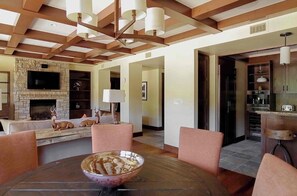 Una sala moderna con chimenea de piedra, una mesa de comedor con sillas y una cocina con armarios y un refrigerador.