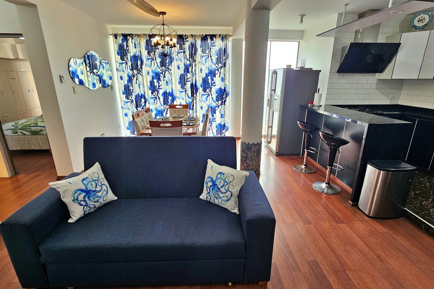 Een moderne woonkamer met een bank, een eethoek met een tafel en stoelen, en een keuken met een bar.