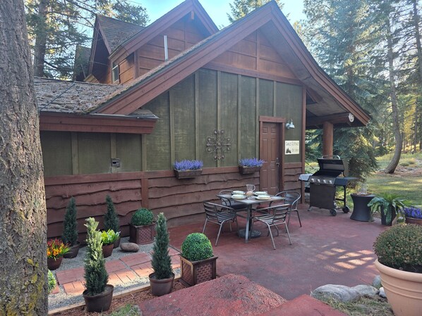 A wooden cabin with a patio area, outdoor seating, and potted plants.