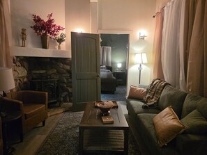 Ein gemütliches Wohnzimmer mit Kamin, einer Couch, einem Couchtisch und einer Tür zu einem anderen Raum.