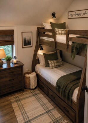 A bunk bed room with a wooden headboard, a bedside table with a lamp, a framed picture on the wall, and a plaid rug on the floor.