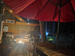 An outdoor patio area with a fire pit, wooden furniture, and a red canopy.