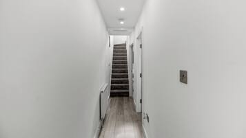 A narrow hallway with a carpeted staircase leading to a door.