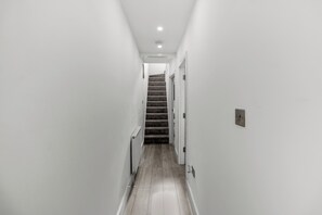 A narrow hallway with a carpeted staircase leading to a door.