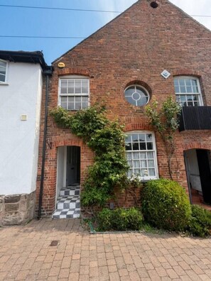 A brick building with a circular window, a door, and a small overhang. - Cosy & spacious 3BR by Warwick castle (Warwickshire)