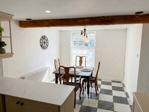 Ein Essbereich mit Schachbrettfußboden, Holzkohlen, einem Tisch und einer Wanduhr.