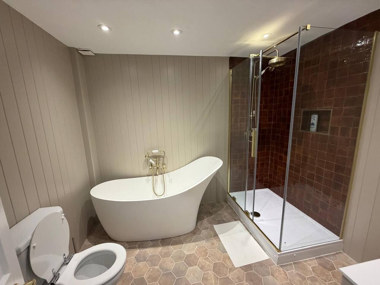Une salle de bain avec une baignoire sur pieds, une douche à parois de verre et des toilettes.