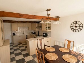 A kitchen with a checkered floor, wooden beams, a dining table with woven placemats, and a wall clock. - Cosy & spacious 3BR by Warwick castle (Warwickshire)