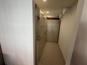 Ein schmaler Korridor mit einem Schrank links und einer Tür rechts.