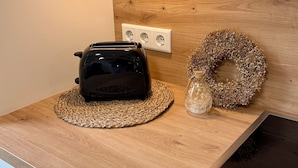 Uma bancada de cozinha com uma torradeira, um descanso de tecido trançado e uma guirlanda decorativa.