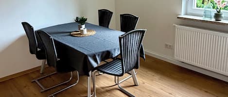 A dining area with a table, chairs, and a clock on the wall.