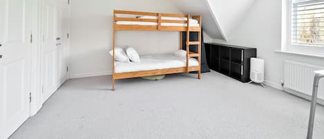 A room with a bunk bed, white walls, a radiator, and a window with blinds.